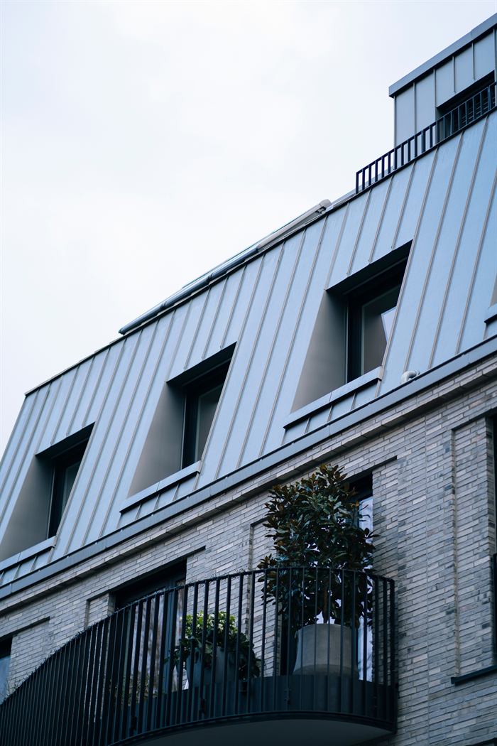 Opgeleverd woongebouw met zinken kap en een balkon met smeedijzeren balustrade